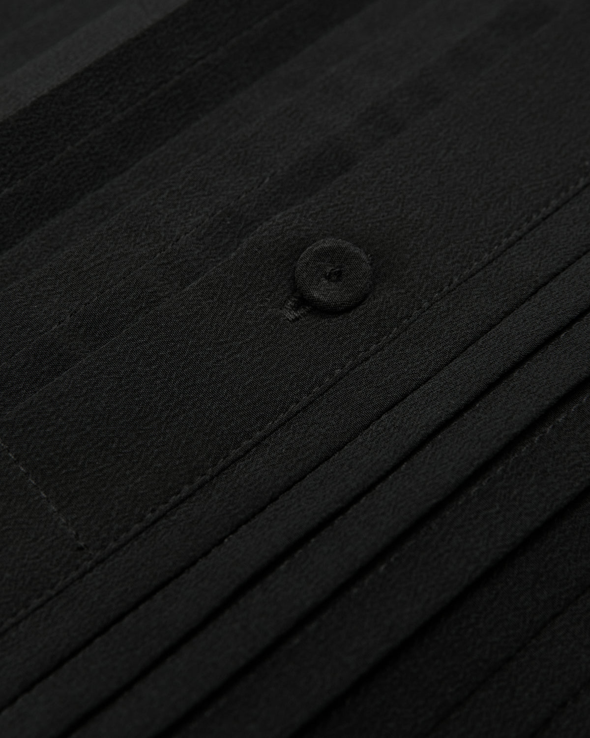 close-up of the black tux shirt pleats and button