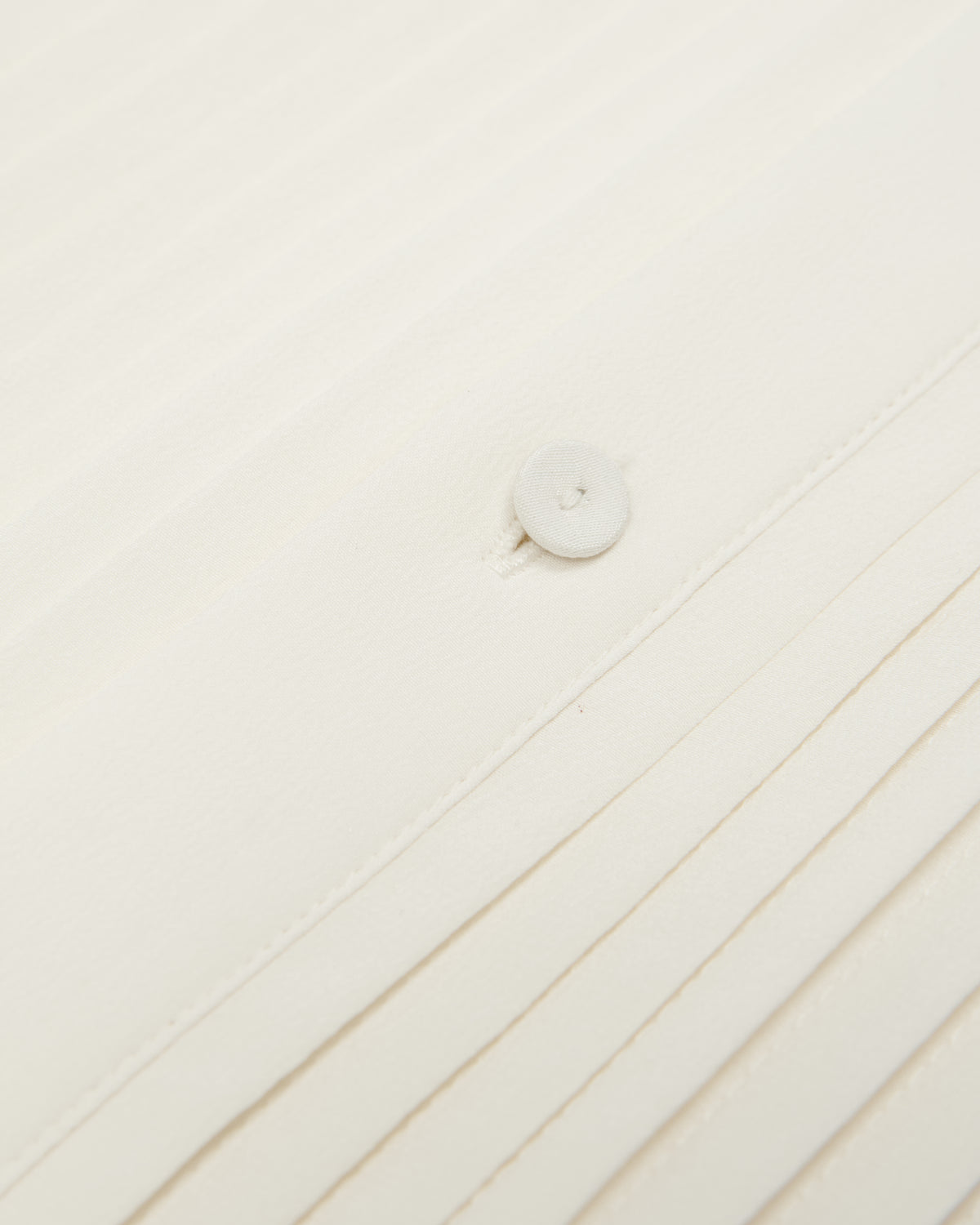 close-up of the ivory tux shirt pleats and button