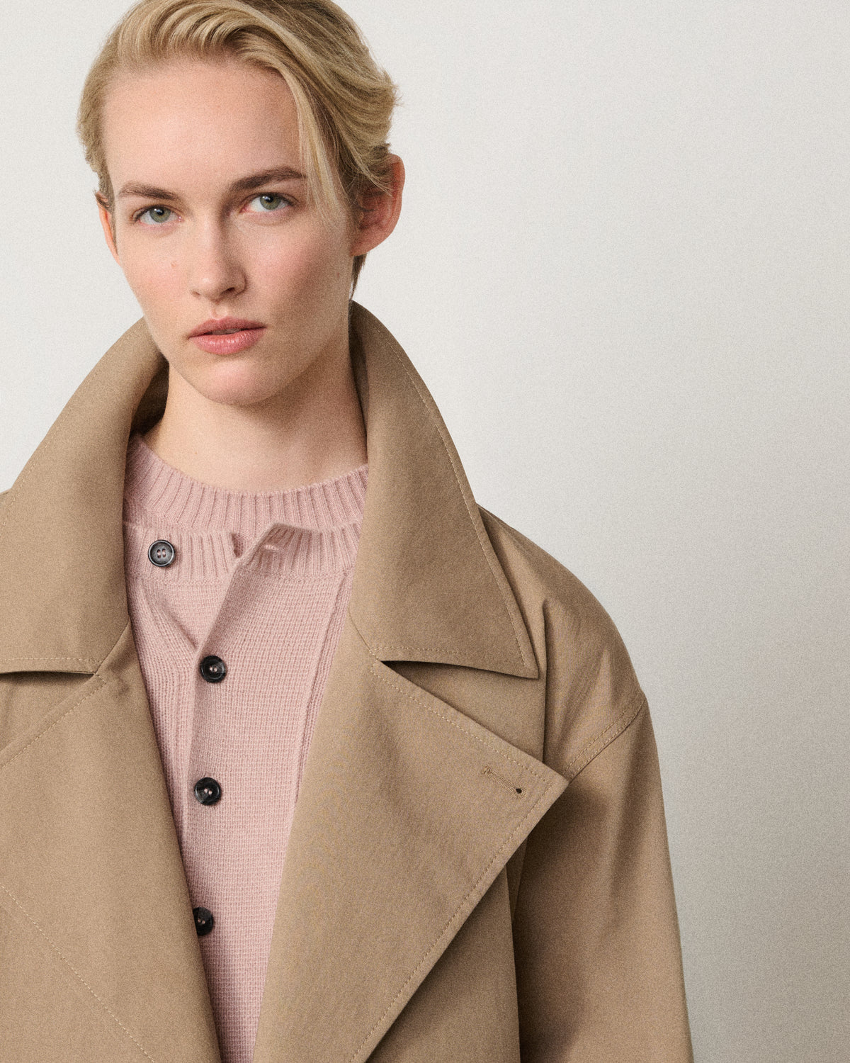 woman wearing the sand trench coat over a pink sweater