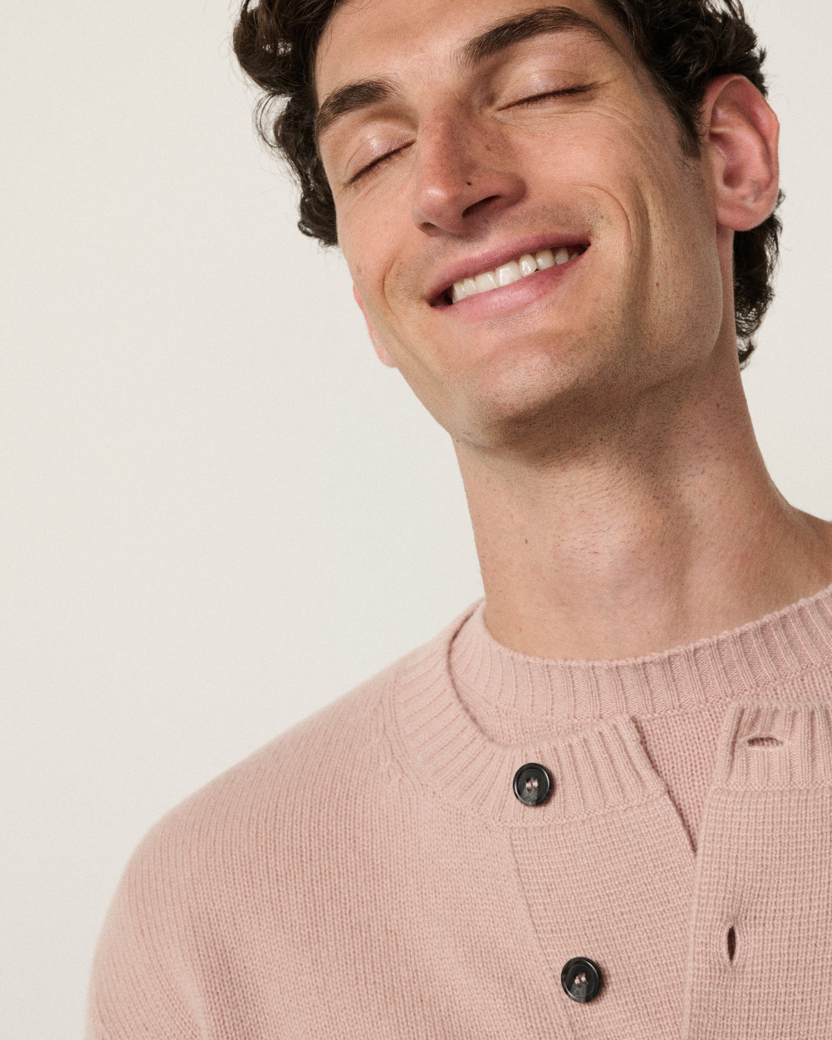 close-up of a man smiling in the blush pink cropped cardigan