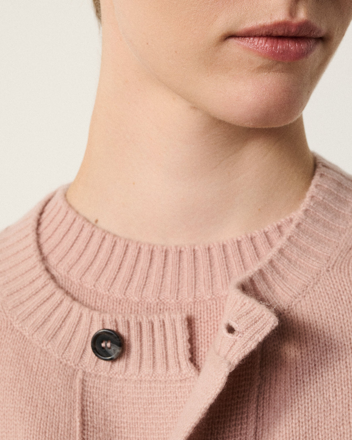 close-up of a woman's neck and the blush pink cardigan collar button