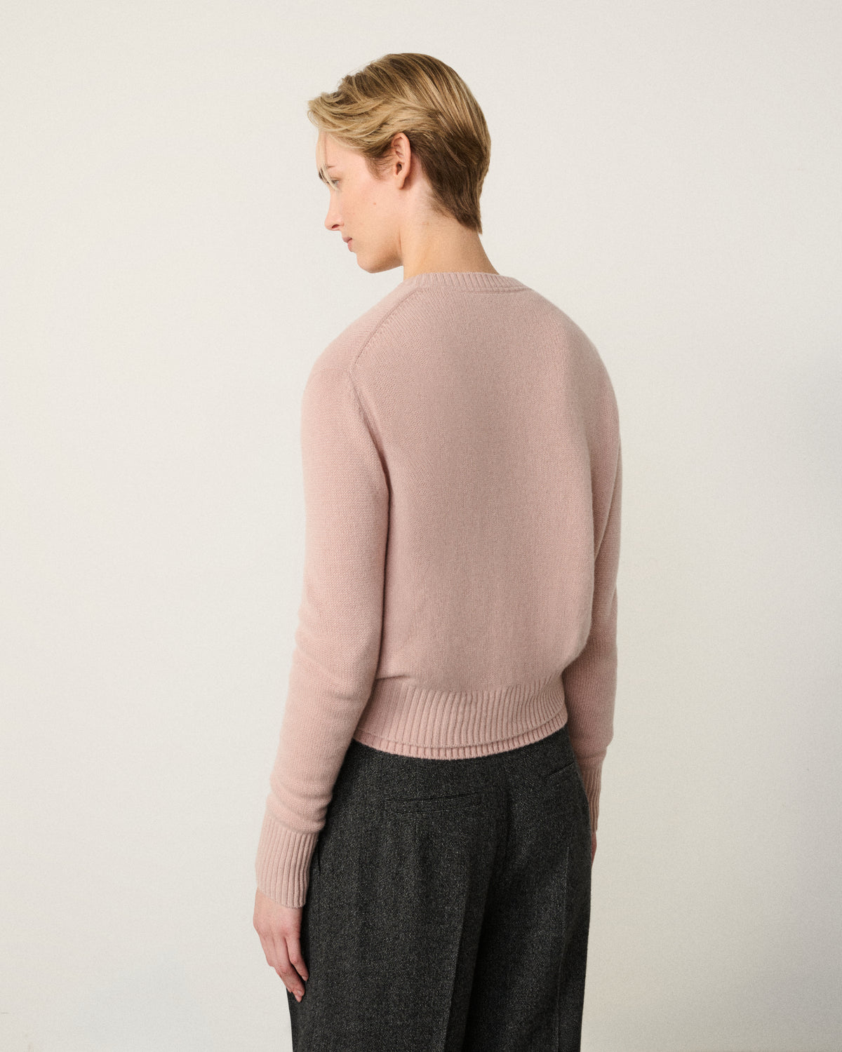 woman in the blush pink cropped cardigan, back view