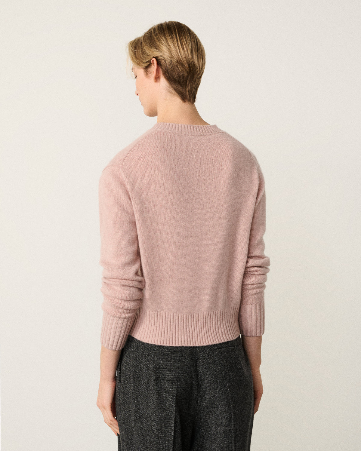 woman in the blush pink cropped sweater, back view