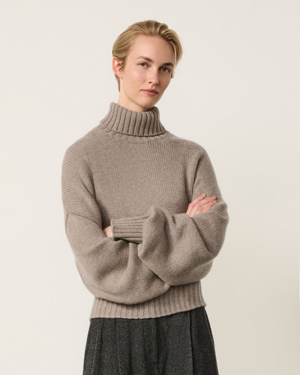 woman wearing the mink turtle neck sweater, arms crossed