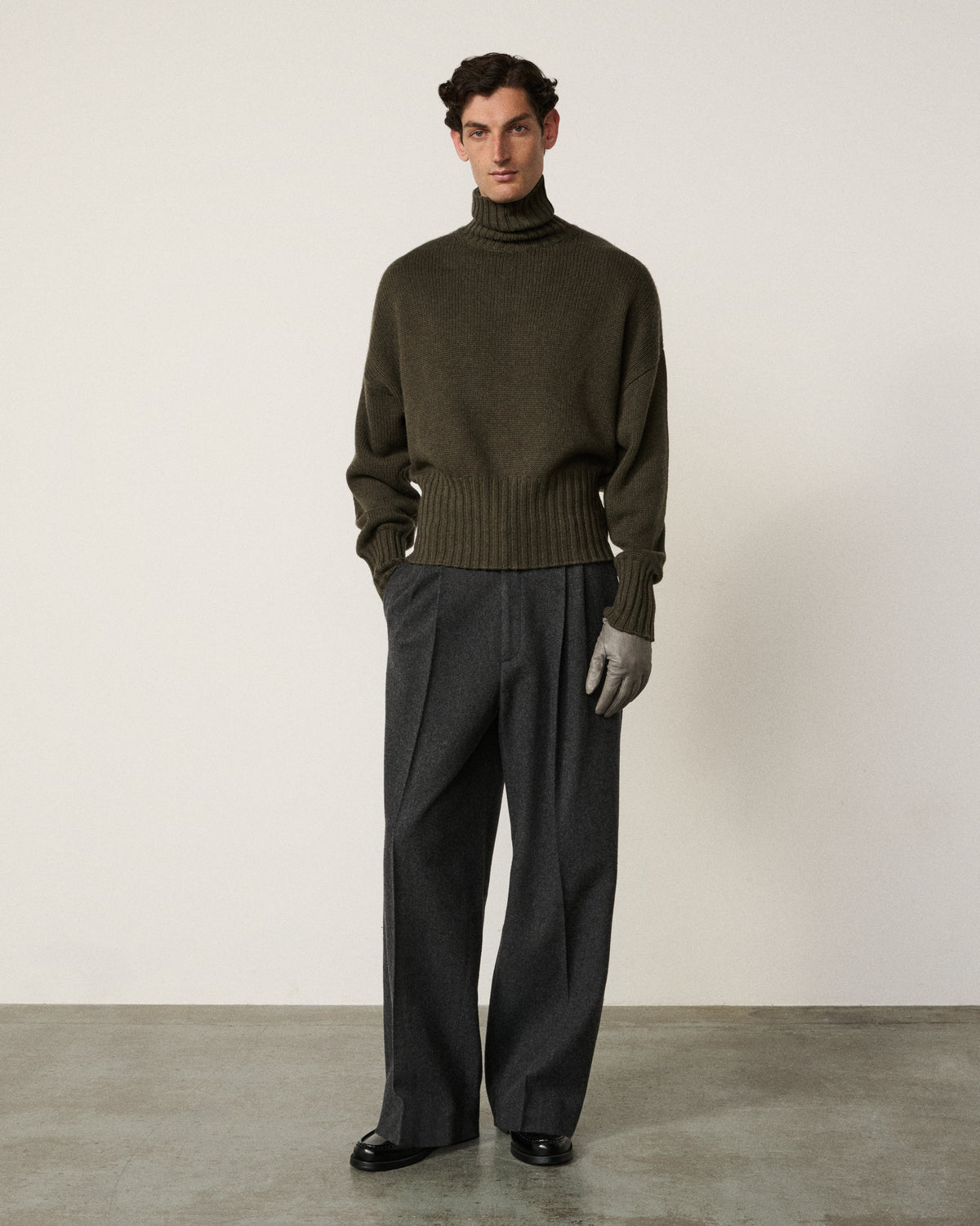 man in the olive relaxed turtle neck sweater, grey trousers