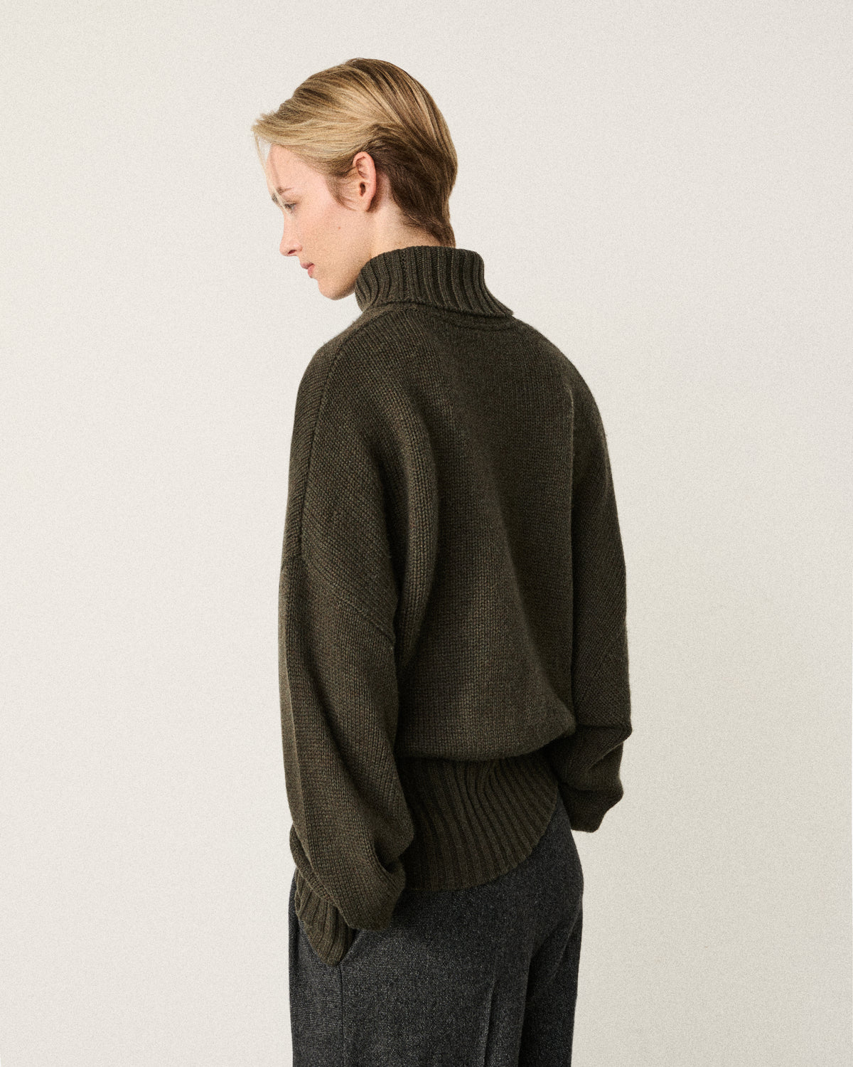 woman in the olive relaxed turtle neck sweater, back view