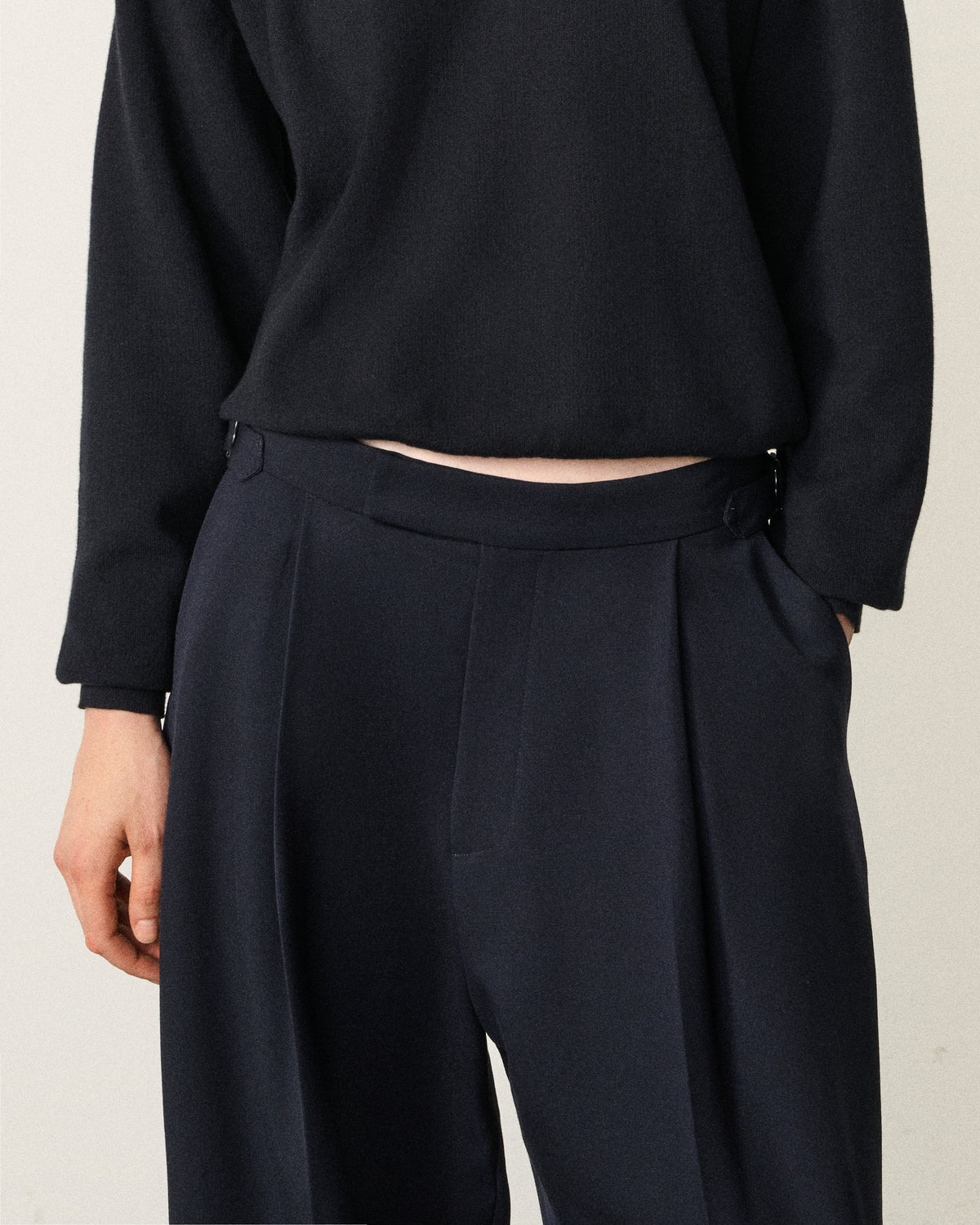 close-up of a woman's torso in the navy tailored pant and black top