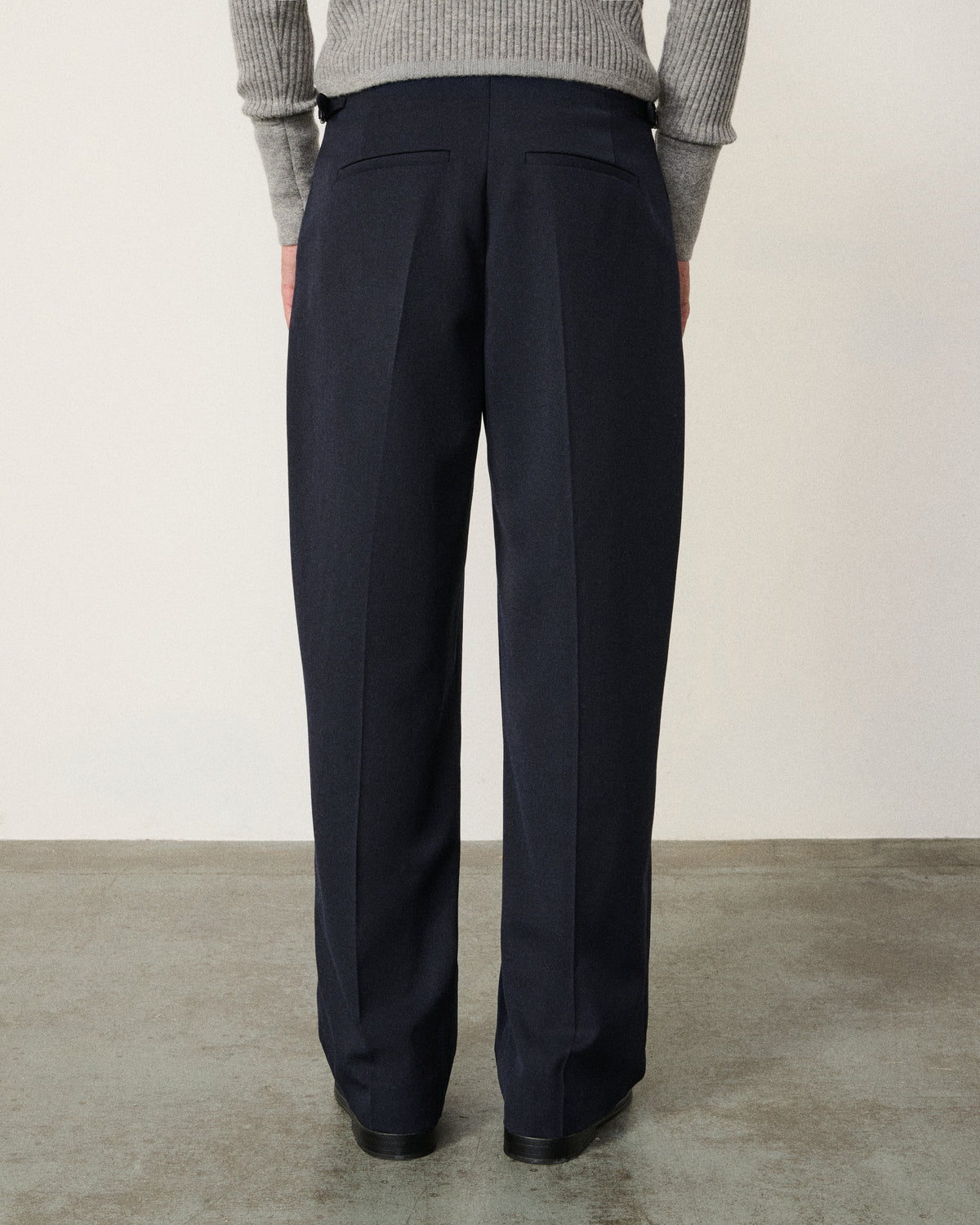 man in the navy everyday tailored pant, back view, hands behind head