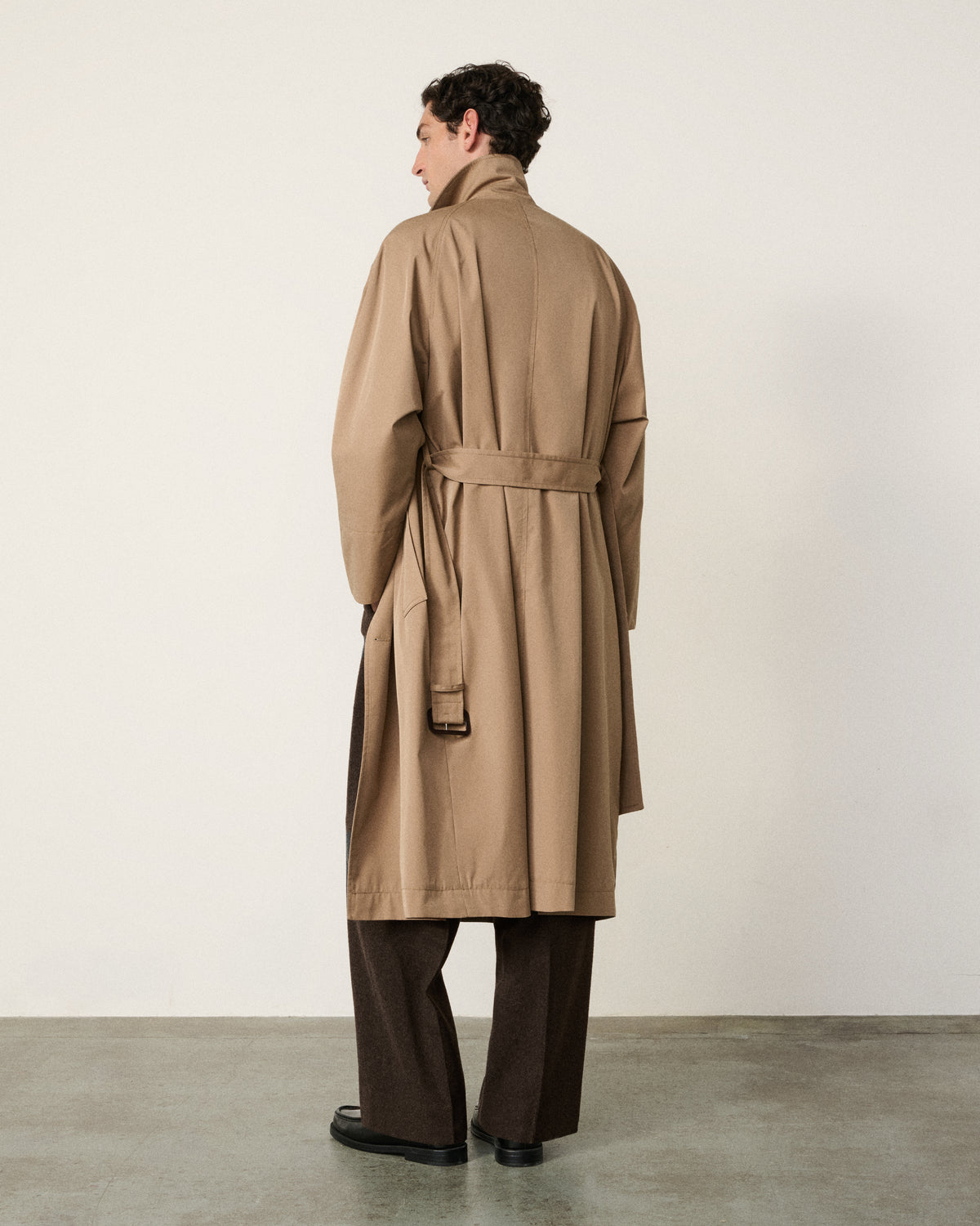 man in the sand trench coat, back view