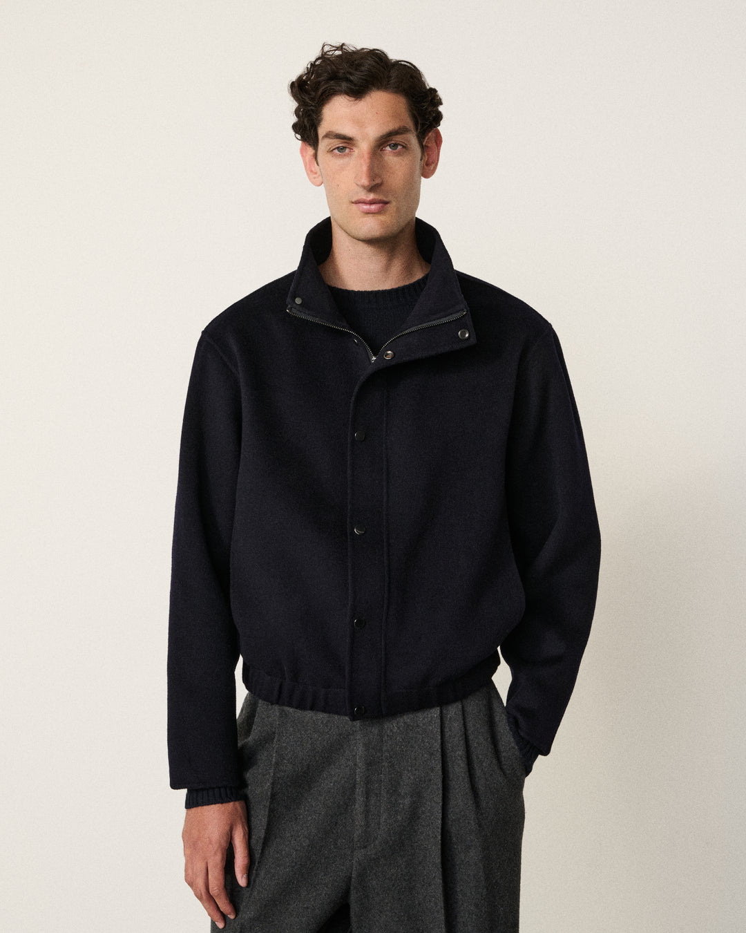 man in the dark navy cropped double faced bomber