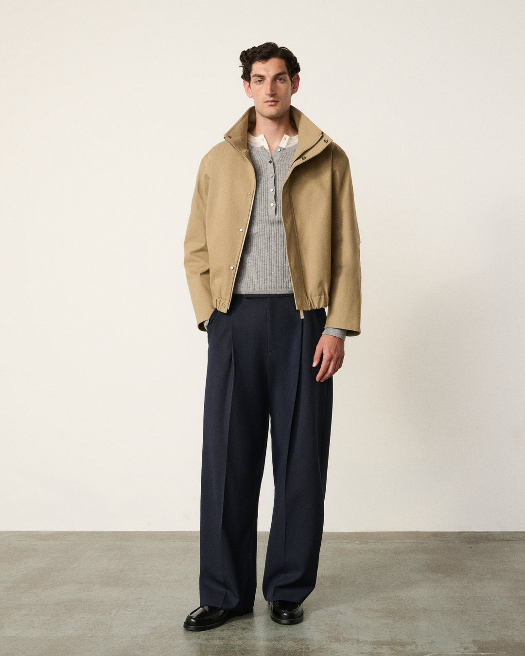 man in the sand cropped cotton bomber, navy trousers