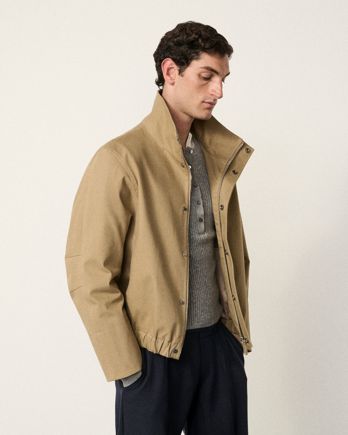 man in the sand cropped cotton bomber, side view