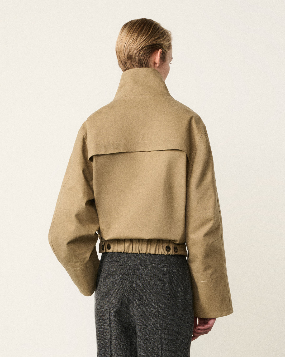 woman in the sand cropped cotton bomber, back view