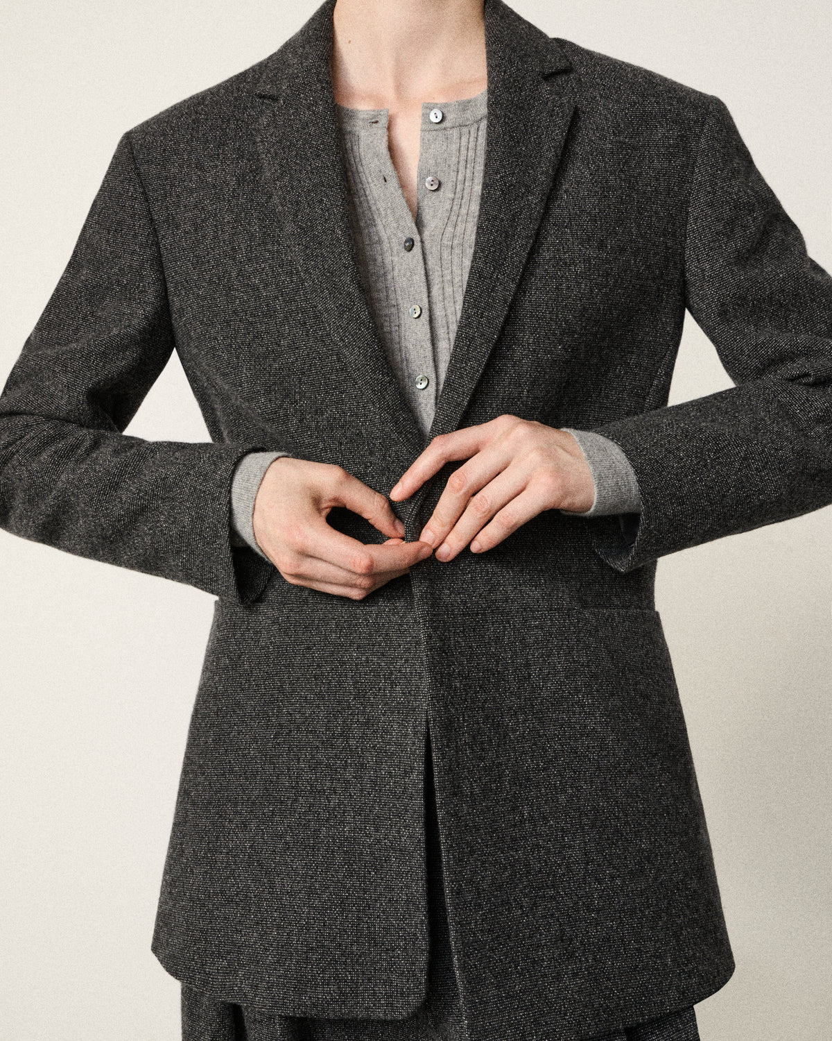 close-up of a woman buttoning the dark grey blazer