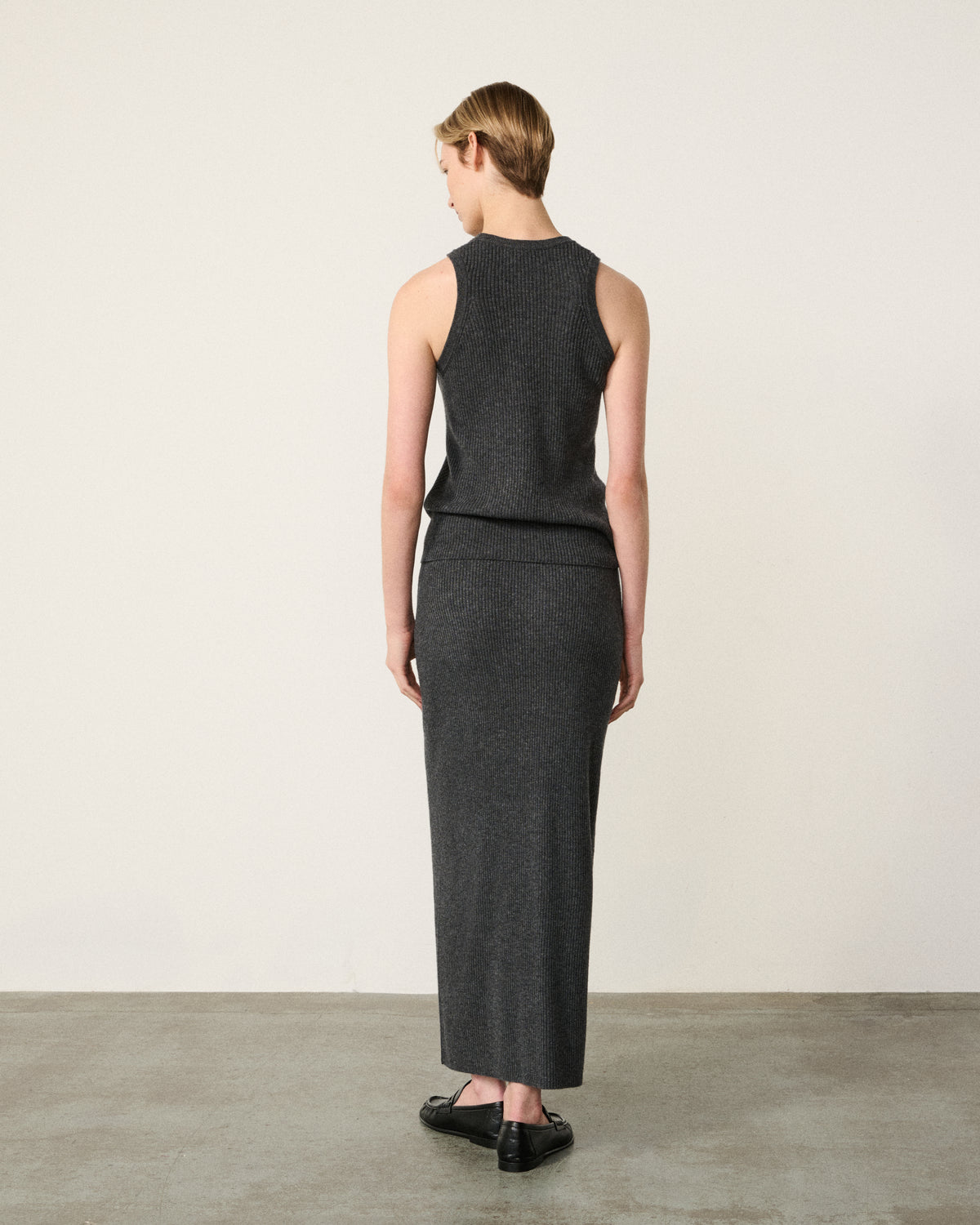 woman in the charcoal grey racer vest, back view