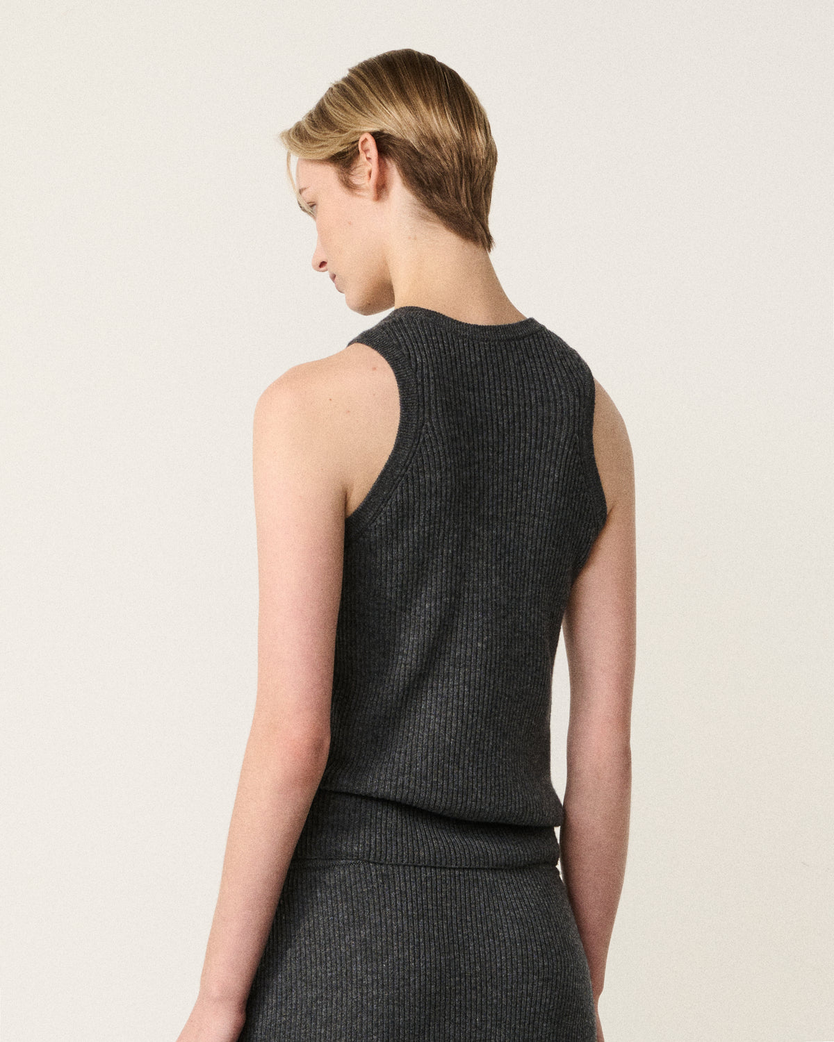 woman in the charcoal grey racer vest, back view