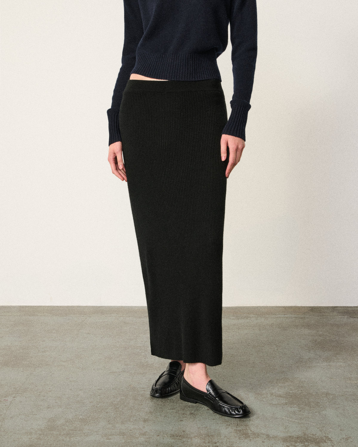 close-up of woman's waist and legs, black ribbed skirt