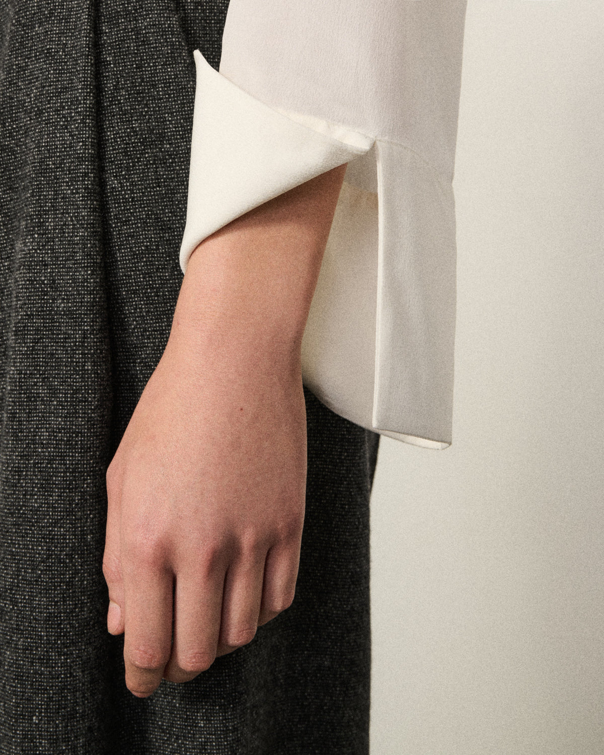 close-up of a woman's hand and cuff of the ivory tux shirt