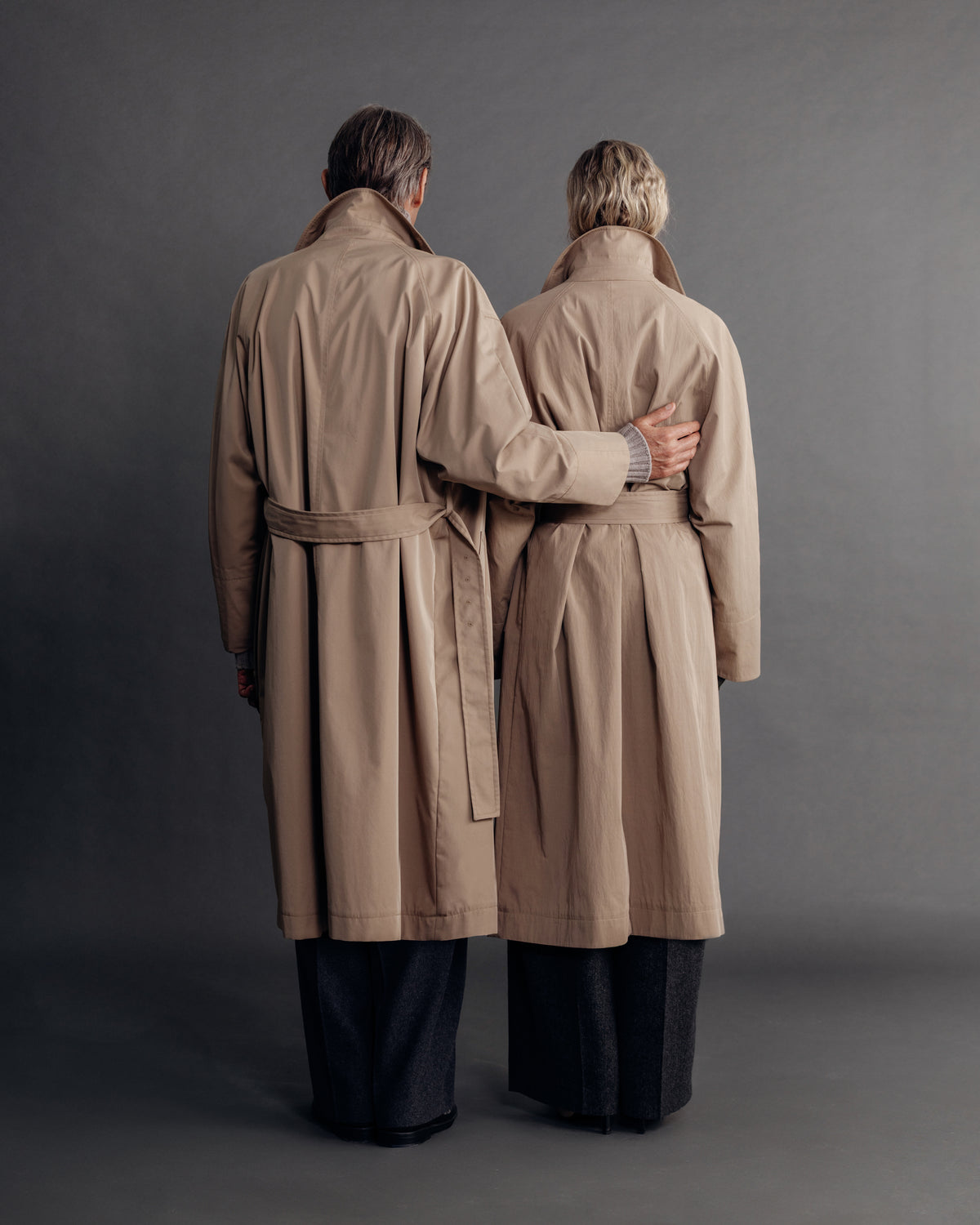 man and woman in the sand trench coat, back view