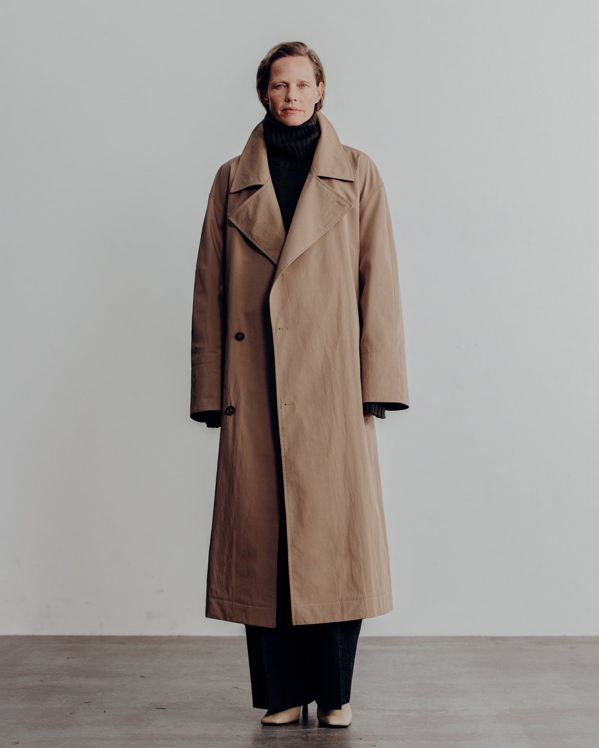 woman in the sand trench coat over a black turtleneck