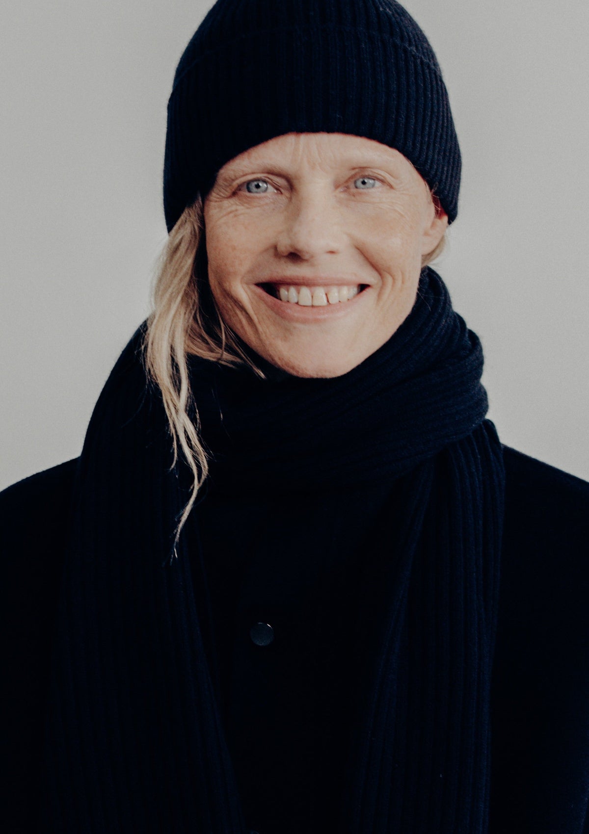 woman smiling wearing the navy beanie and scarf