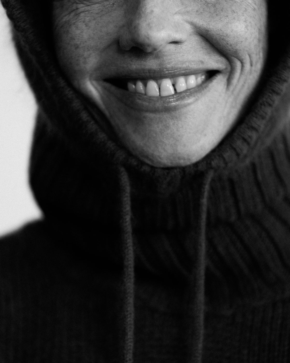 close-up of a woman smiling in the ribbed cashmere snood, black and white